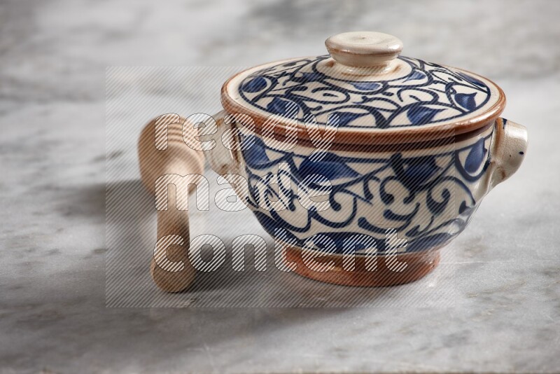 Decorative pottery pot with wooden honey dipper on the side on grey marble background