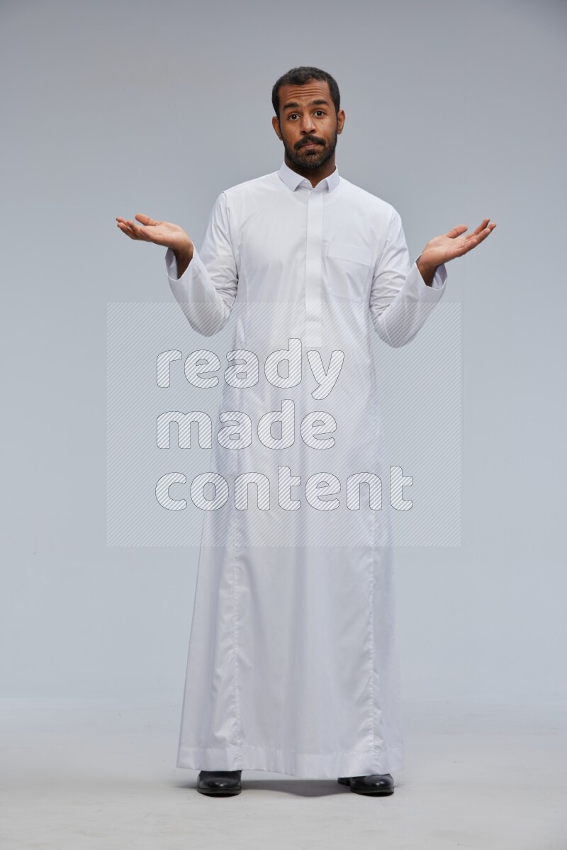 Saudi man Wearing Thob standing interacting with the camera on Gray background