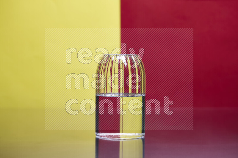 The image features a clear glassware filled with water, set against yellow and red background