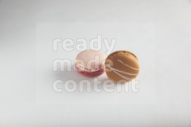 45º Shot of of two assorted Brown Irish Cream, and Pink Litchi Raspberry macarons on white background