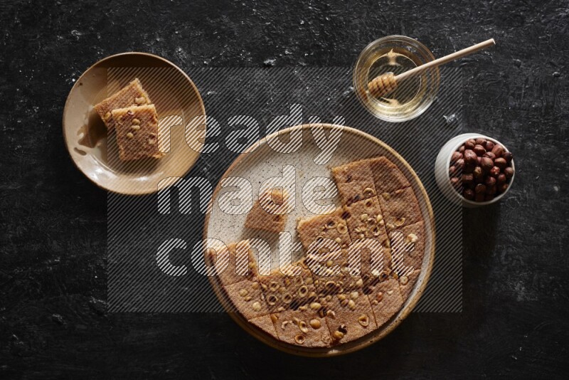 بسبوسة بالمكسرات والعسل علي خلفية سوداء خشبية