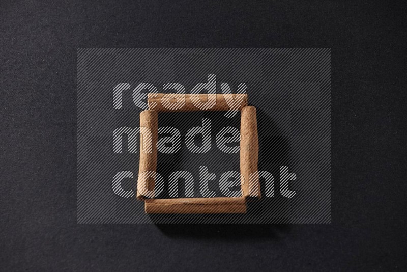 A single square of cinnamon sticks on black flooring