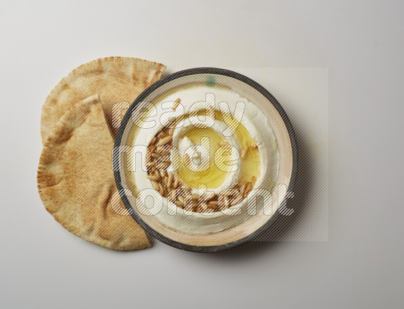 Lebnah garnished with pine nuts in a pottery plate on a white background