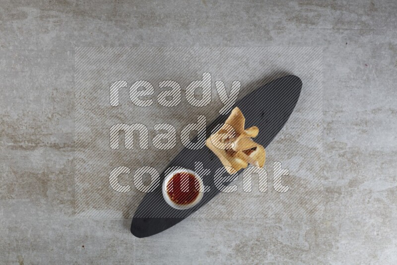 wonton cups with soy sauce ramkin on oval slate on grey textured counter top