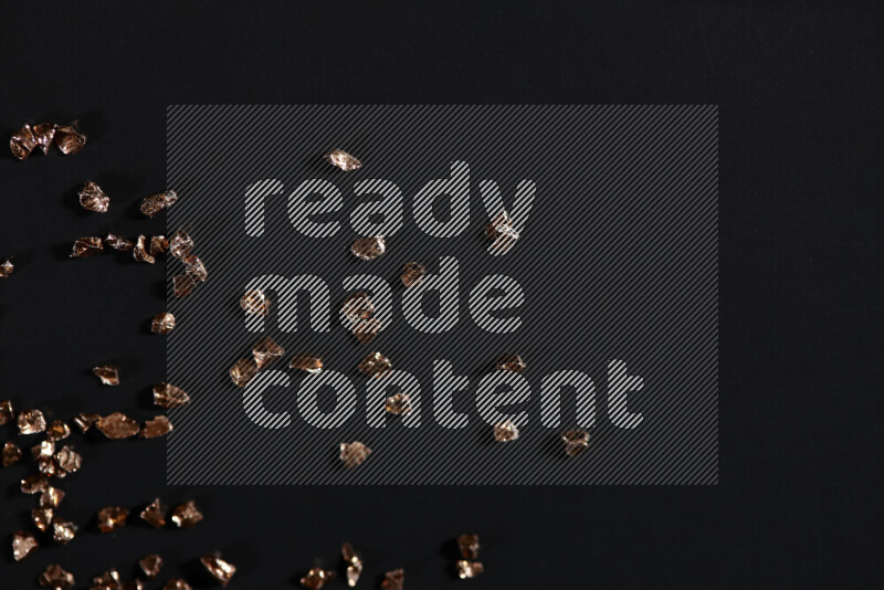 Bronze shimmering fragments of glass scattered on a black background