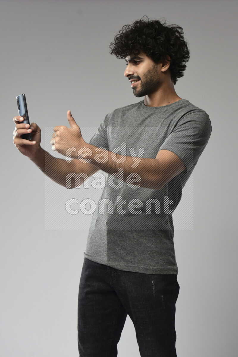 A man wearing casual standing and shooting with his phone on white background