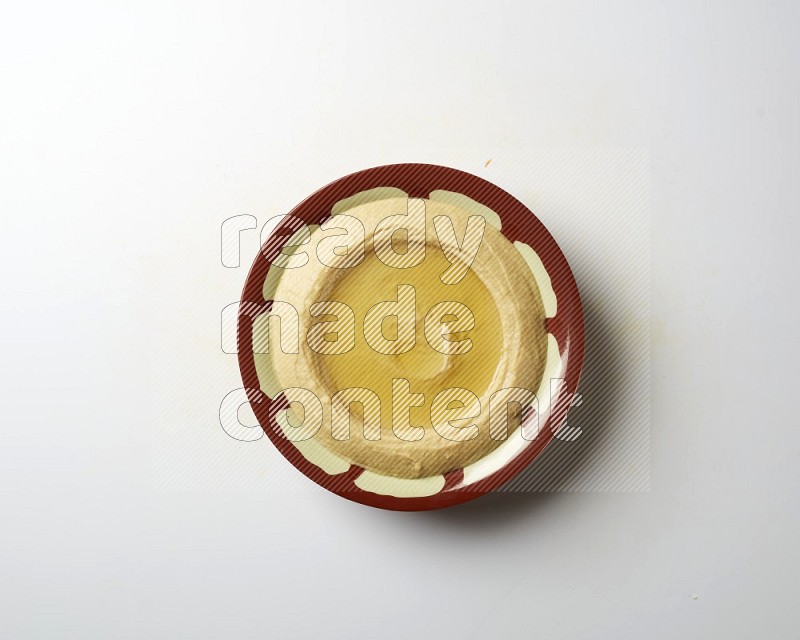 Hummus in a traditional plate garnished with olive oil on a white background