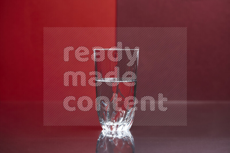 The image features a clear glassware filled with water, set against red and dark red background