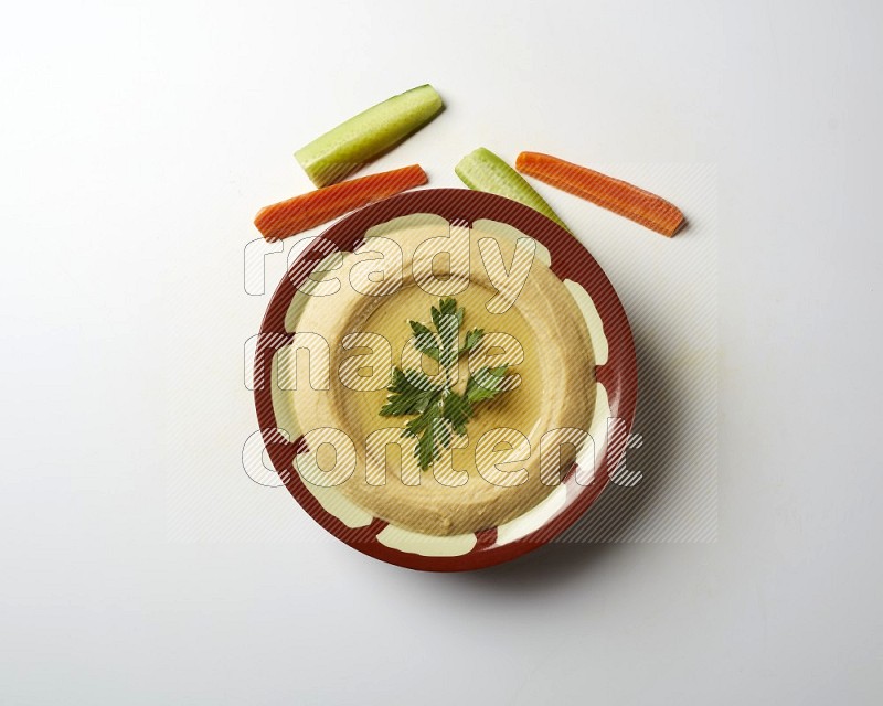 Hummus in a traditional plate garnished with parsley on a white background