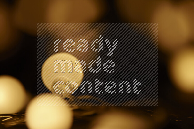 Light bulbs glowing against backdrop of golden bokeh