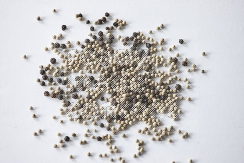 حبوب الفلفل المختلطة السوداء والبيضاء على أرضية بيضاء