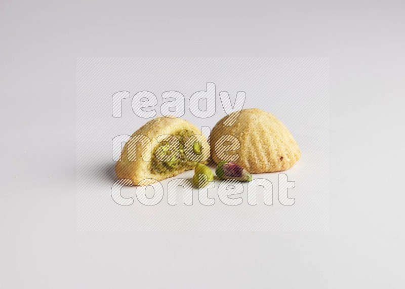 Two Pieces of Maamoul filled with pistachio paste  one of them is cut direct on white background