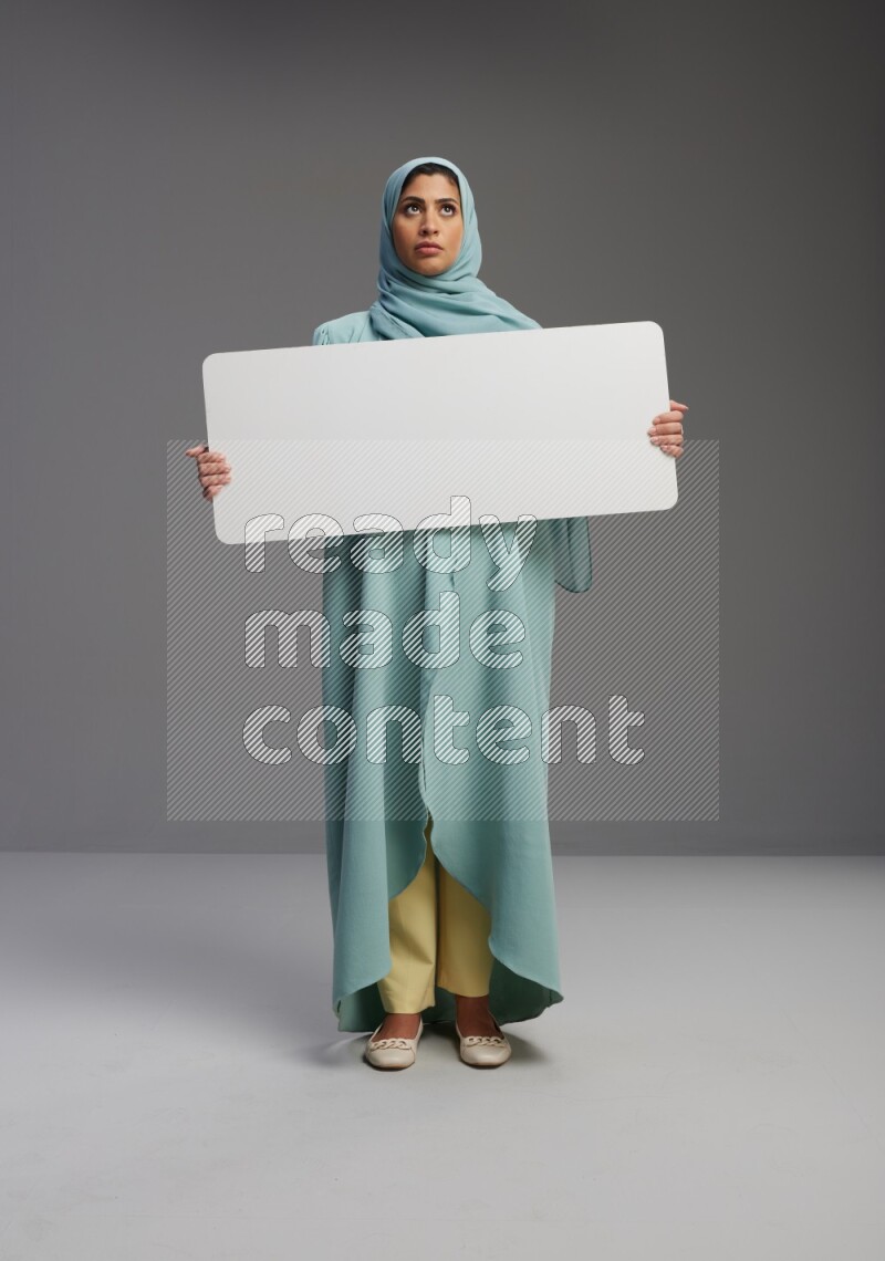 Saudi Woman wearing Abaya standing holding board on Gray background