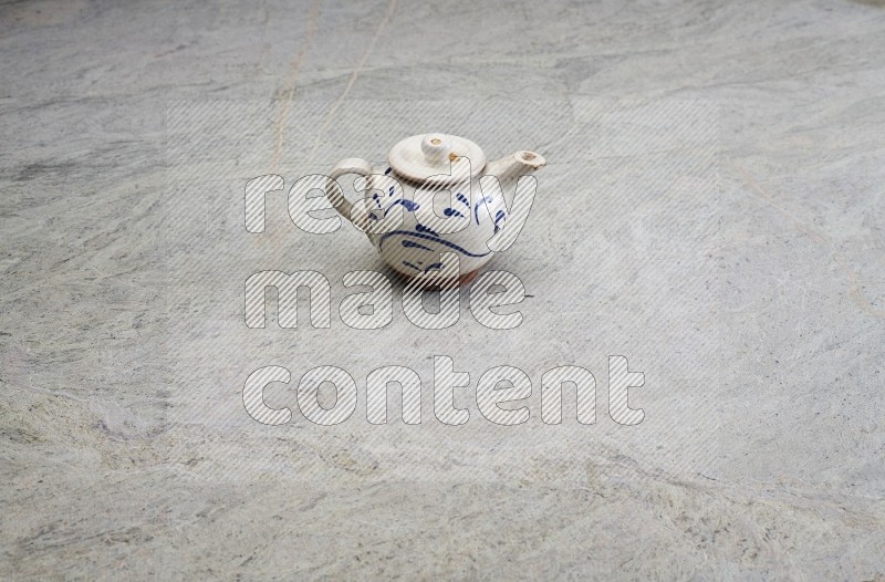 A Pottery Teapot On Grey Marble Flooring