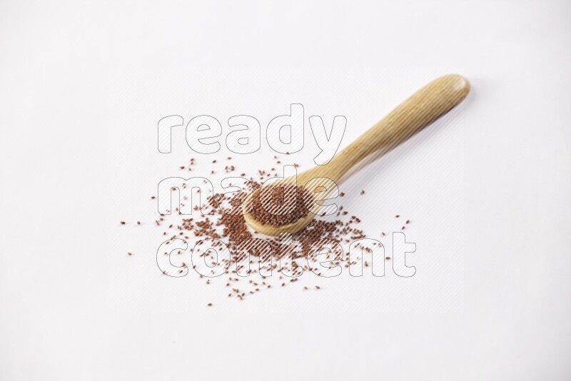 A wooden spoon full of garden cress seeds on a white flooring