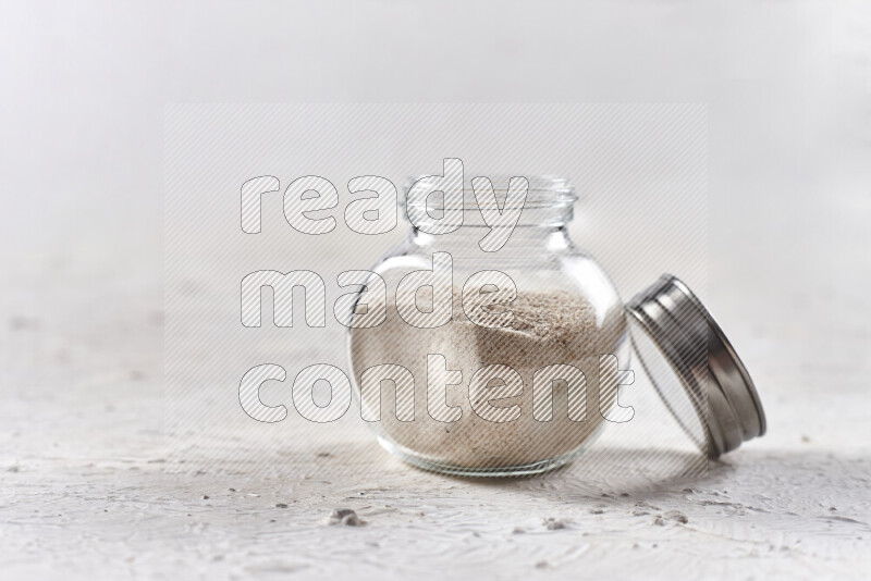 A glass jar full of onion powder on white background