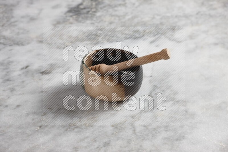 Multicolored pottery bowl with wooden honey dipper in it on grey marble background
