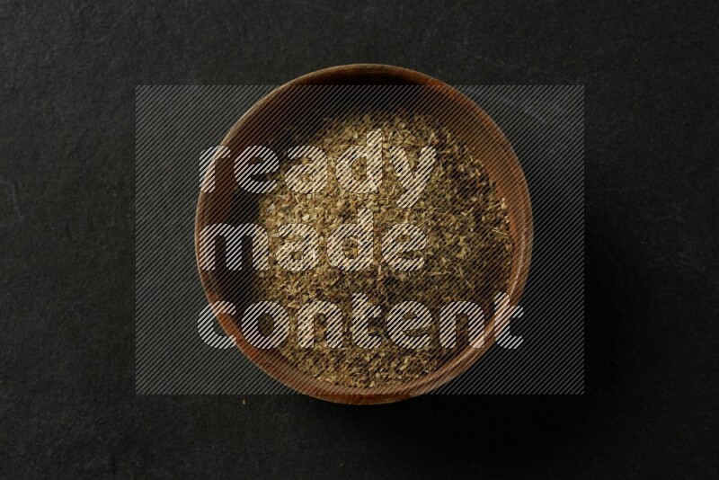 wooden round sauce bowl filled with herbs on grey textured countertop