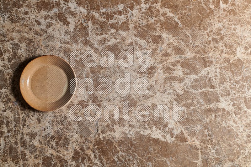 Top View Shot Of A Beige Pottery Circular Plate On beige Marble Flooring