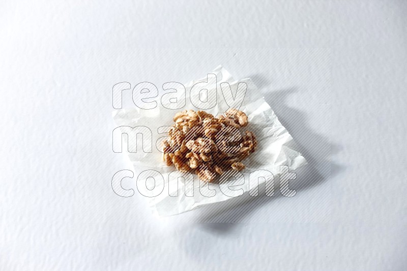 Peeled walnuts on a crumpled piece of paper on a white background in different angles