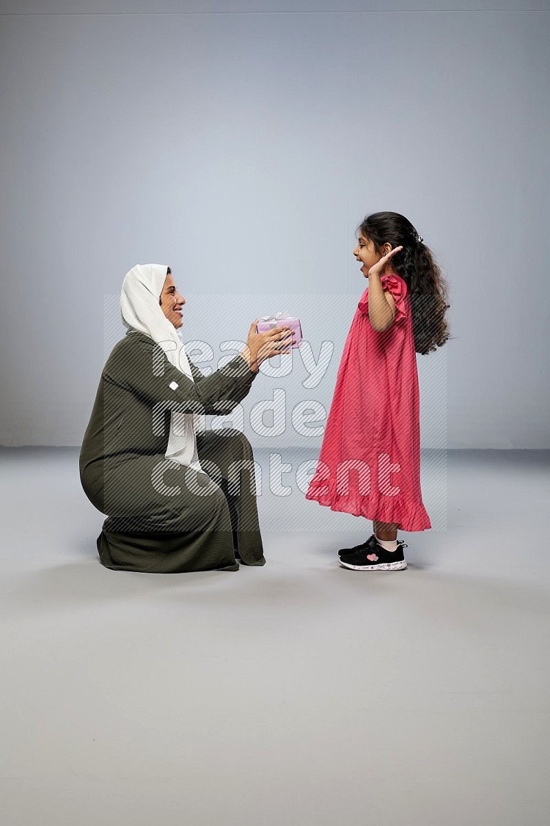 A girl giving a gift to her mother on gray background
