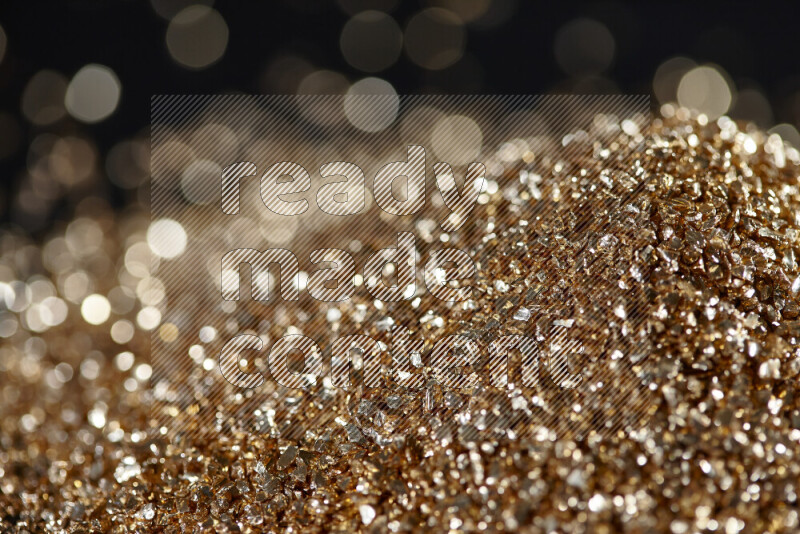 Gold shimmering fragments of glass scattered on a black background