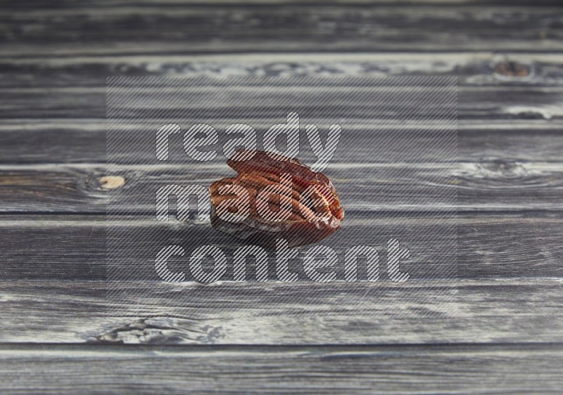 pecan stuffed madjoul date on a wooden grey background