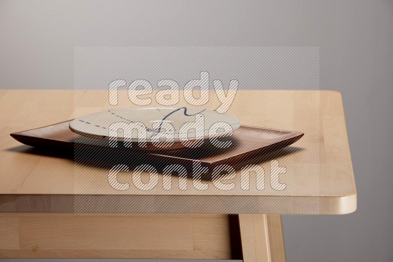 multicolored plate on a rectangular wooden tray on the edge of wooden table