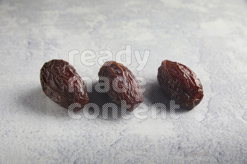 three madjoul dates on a light grey background