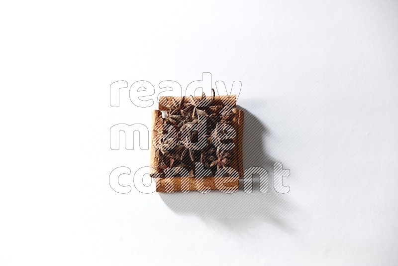 A single square of cinnamon sticks full of star anise on white flooring