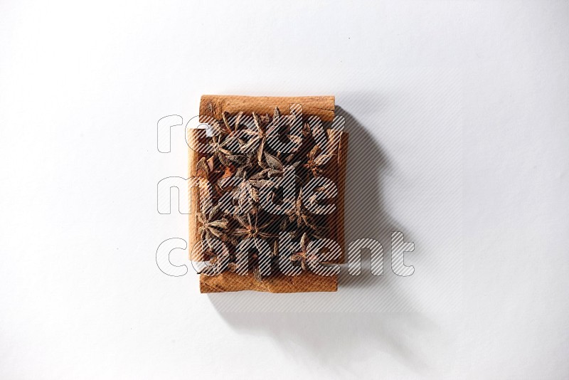 A single square of cinnamon sticks full of star anise on white flooring