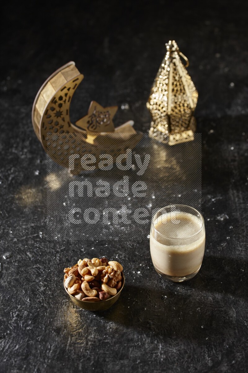 Nuts in a metal bowl with Nuts smoothie beside golden lanterns in a dark setup