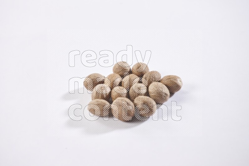 A bunch of whole nutmeg seeds on a white flooring