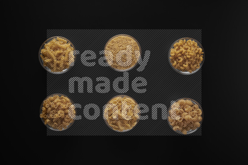 أنواع مختلفة من المعكرونة في أوعية زجاجية علي خلفية سوداء