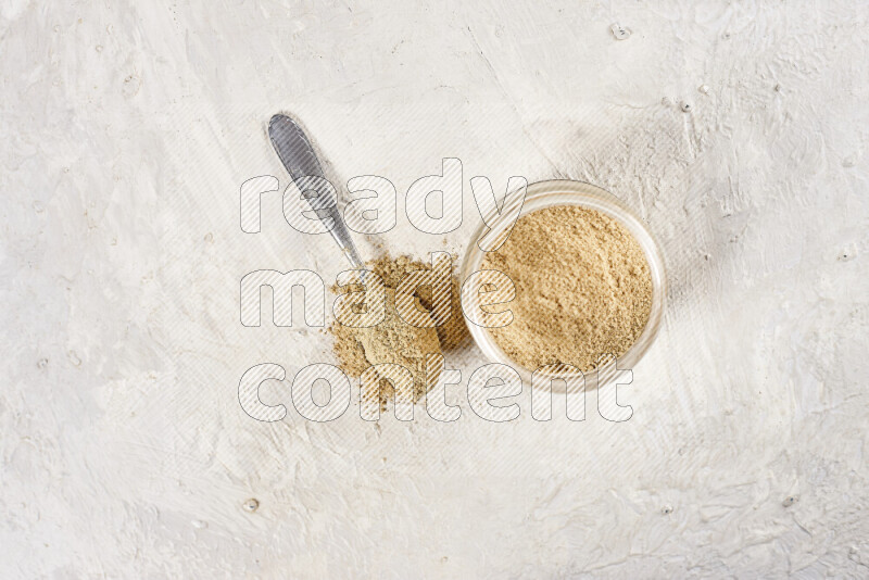 A glass jar full of ground ginger powder on white background