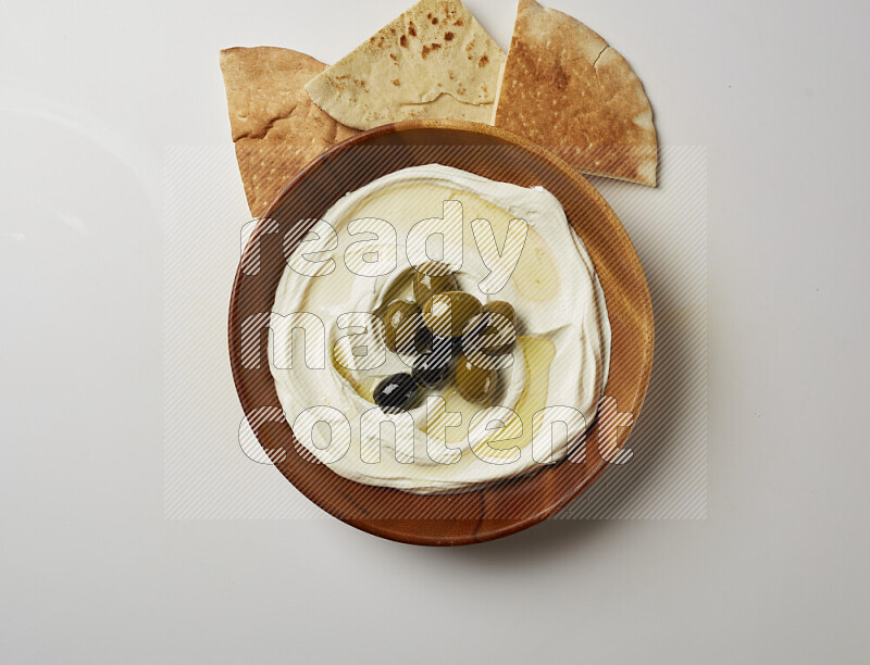 Lebnah garnished with whole olives in a wooden plate on a white background