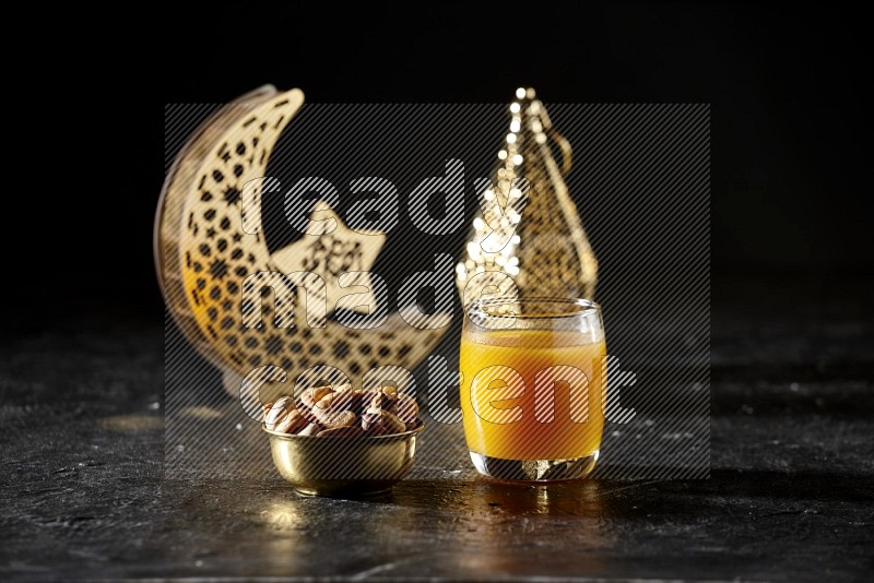 Nuts in a metal bowl with qamar el din beside golden lanterns in a dark setup