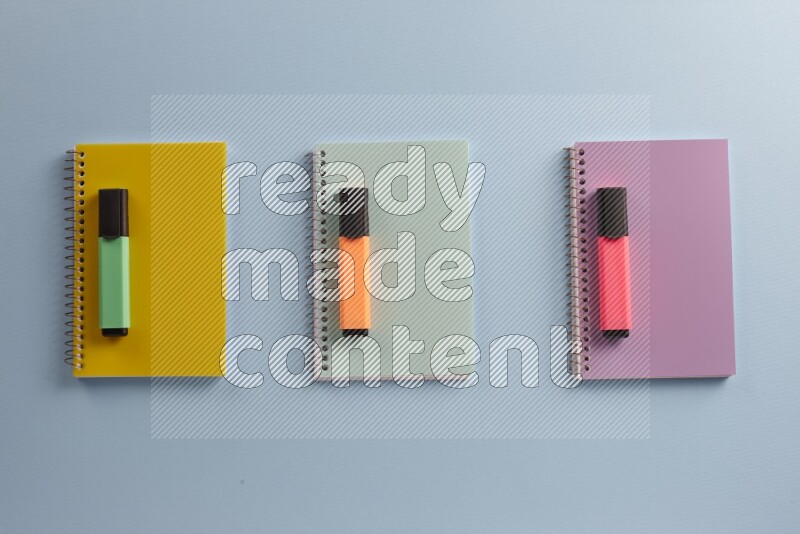 Multicolored notebooks with different school supplies on blue background