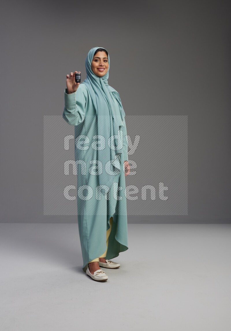 Saudi Woman wearing Abaya standing holding car key on Gray background