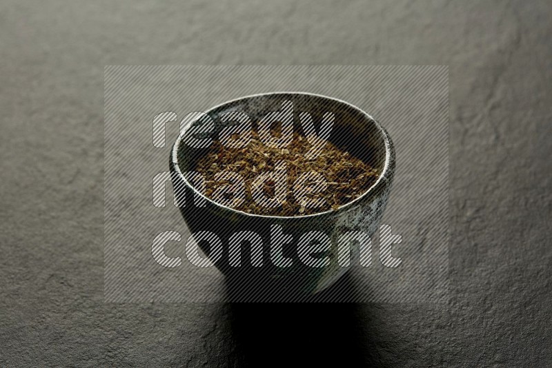 multi color round sauce bowl filled with herbs on grey textured countertop
