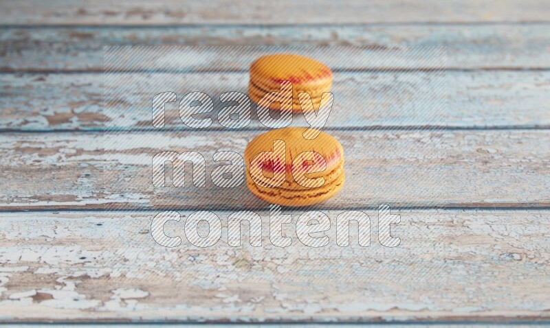 45º Shot of two orange Exotic macarons on light blue wooden background