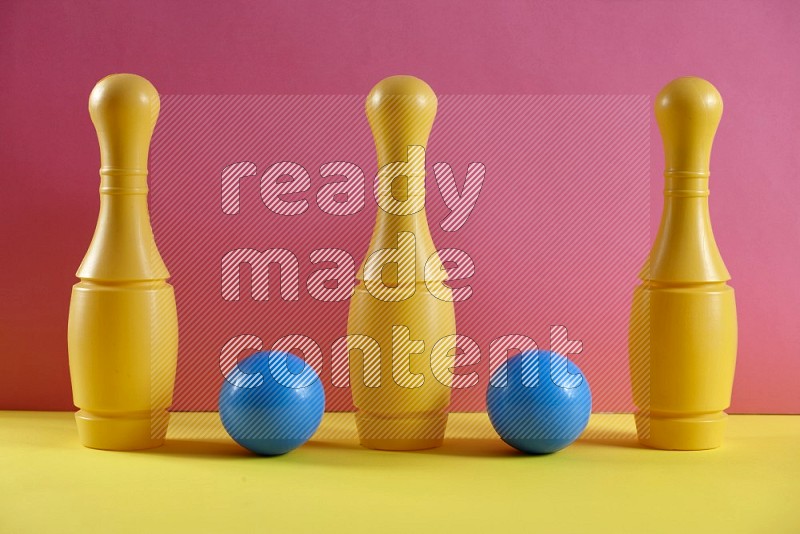 Plastic bowling pins with balls on pink and yellow background (kids toys)