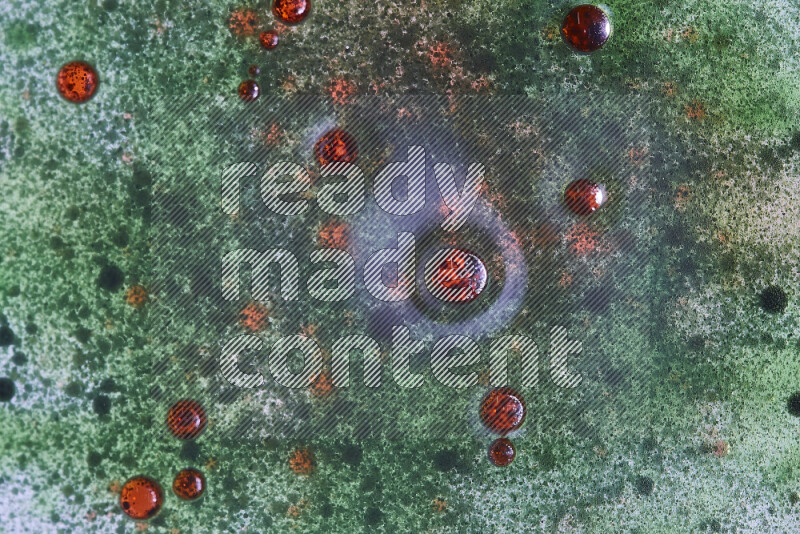 Close-ups of abstract red and green watercolor drops on oil Surface on green background