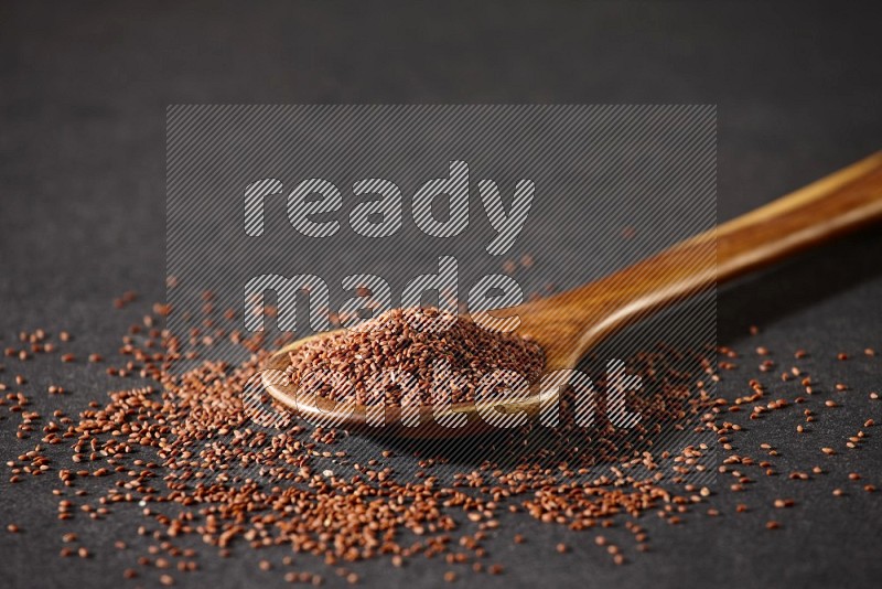 A wooden ladle full of garden cress and seeds spreaded beside it on a black flooring in different angles