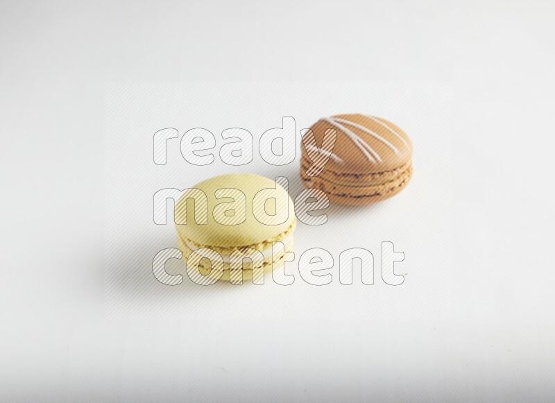 45º Shot of of two assorted Brown Irish Cream, and Yellow Lime macarons on white background