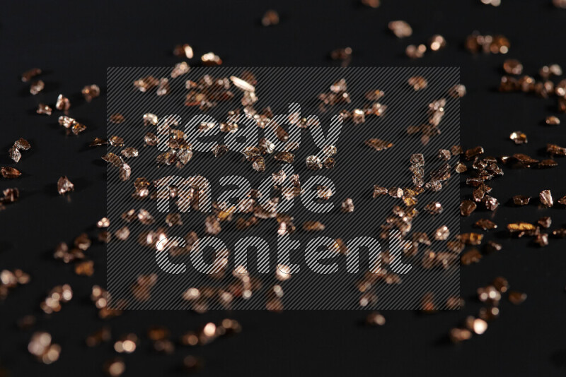 Bronze shimmering fragments of glass scattered on a black background