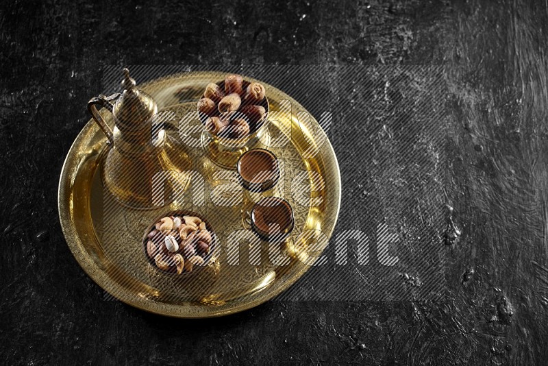Nuts with dates and a drink on a metal tray in a dark setup