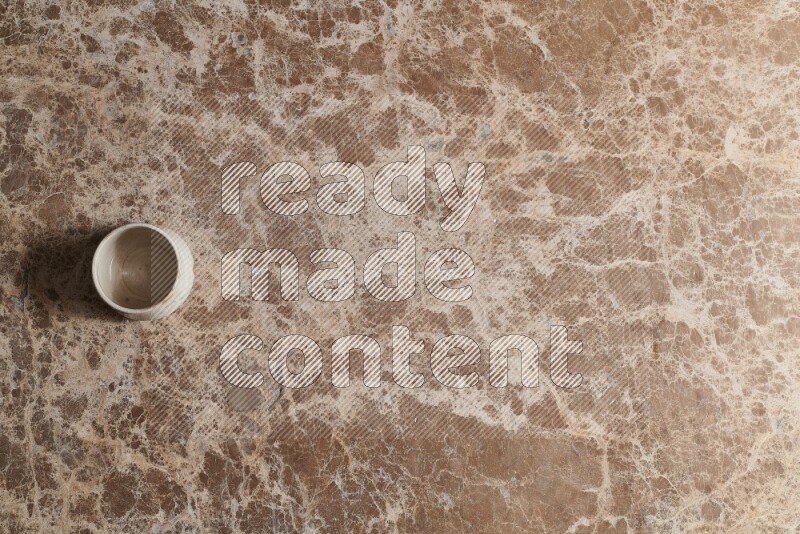 A multicolored pottery bowl on beige marble background