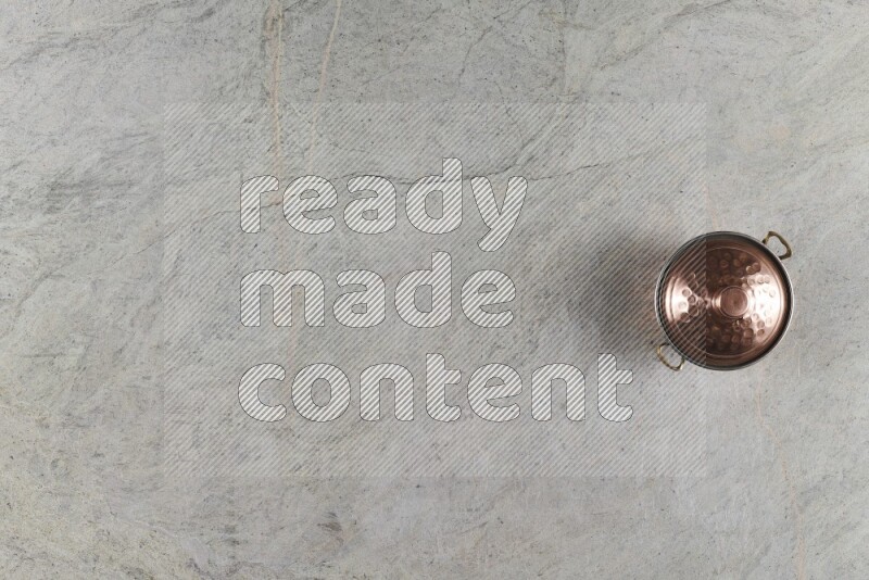 A small copper pot on grey marble background