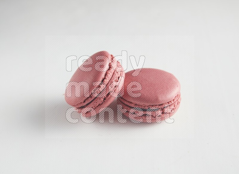 45º Shot of two Pink Raspberry macarons on white background